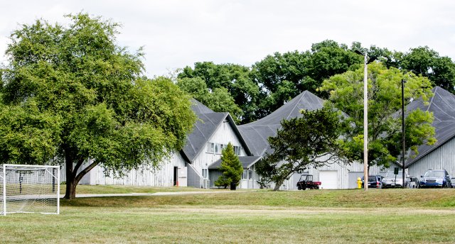 A white building with a grey roof surrounded by trees