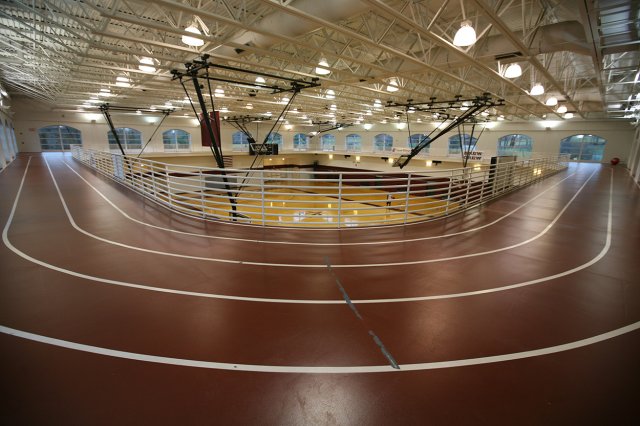 An indoor running track with a basketball court visible below