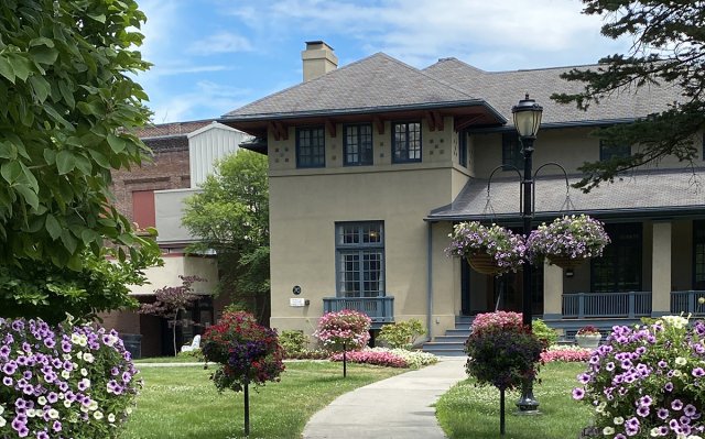 A cream and light blue house with several clusters of flowers in the foreground