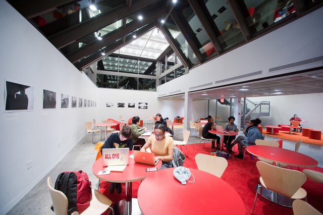 Students sitting at a red round table using laptop computers
