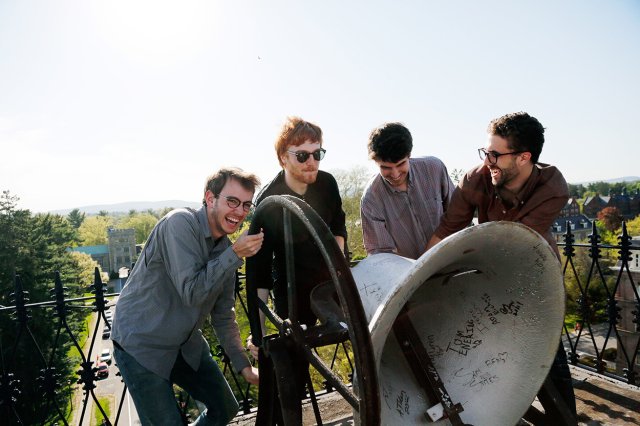 Four students ringing a large bell