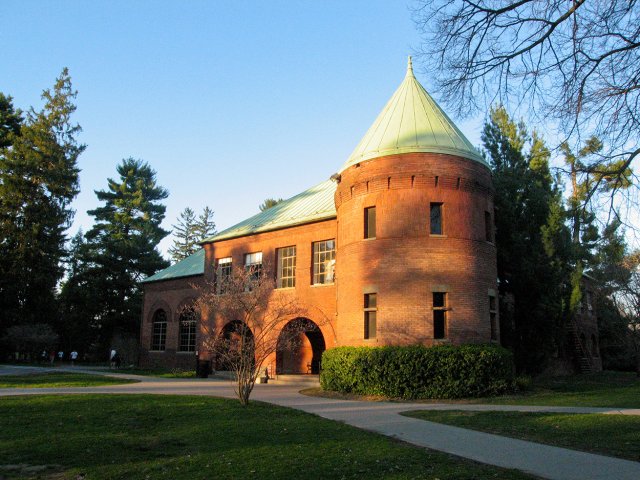 An orange building with a green roof and circular tower