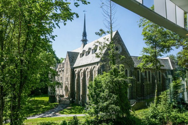 A large gothic-style building surrounded by greenery